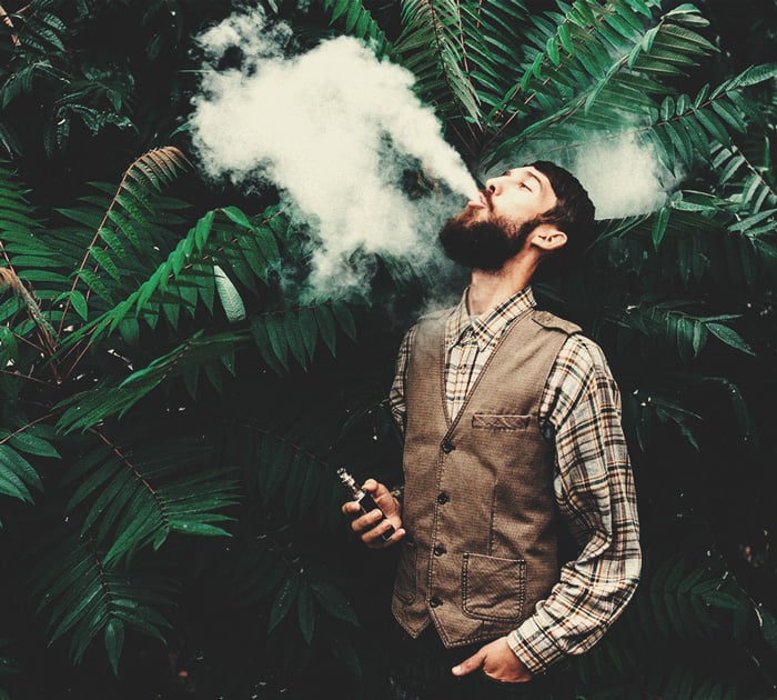 A man sitting outdoors, enjoying a smoke from a vaporizer, highlighting the experience of vaping hash.