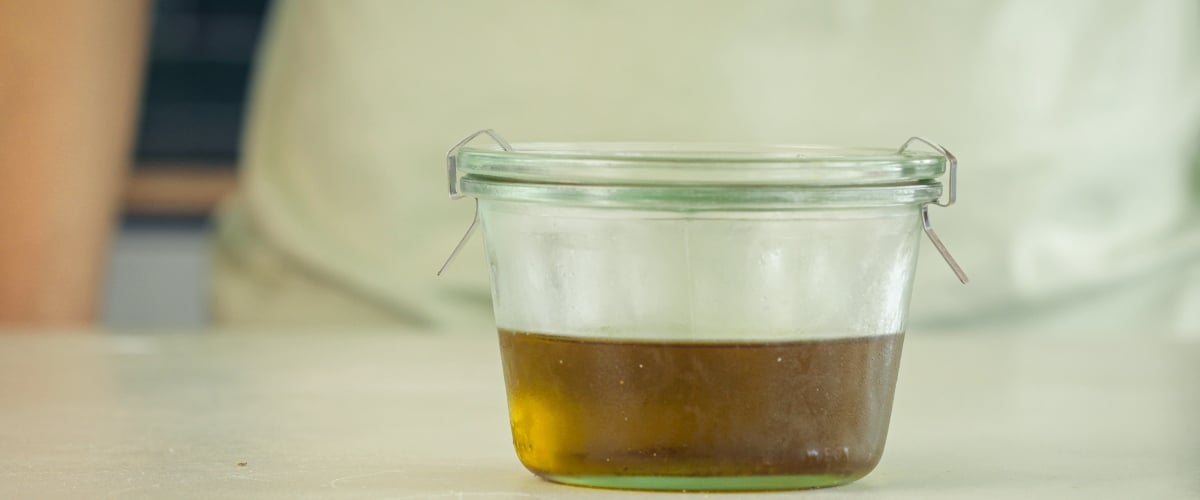 Pouring cannabis-infused MCT oil into an airtight amber glass bottle for storage, final step of the infusion process