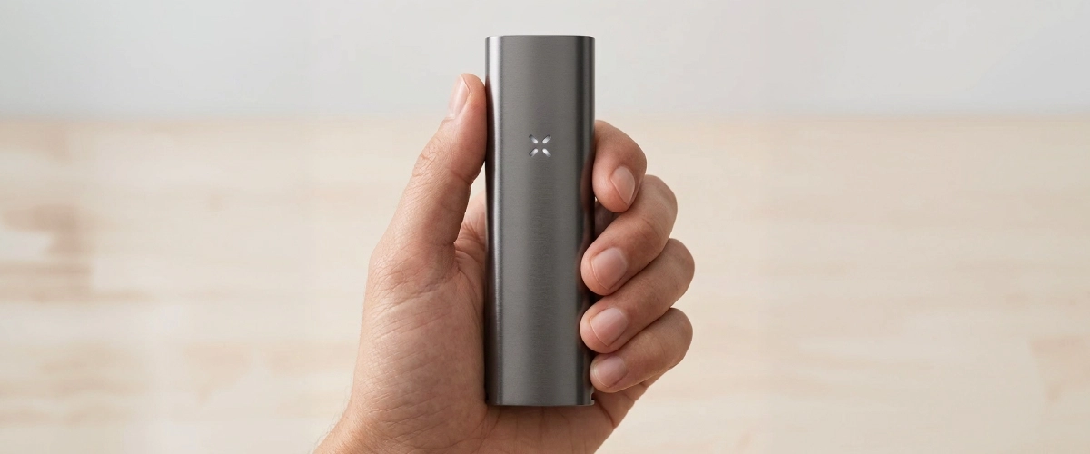 PAX Four vaporizer held in one hand, showing its slim matte body, compact size, and LED petal indicator on the front