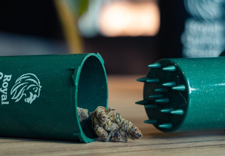 Grindtainer for Easy Cannabis Storage and Grinding Image of a compact grindtainer with cannabis buds on a wooden surface.